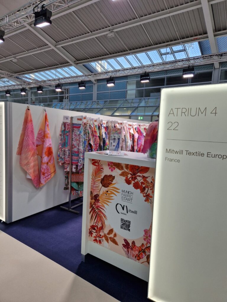 Mitwill Textile Europe booth at Munich Fabric Start 2025, with colorful fabric displays and floral-themed signage