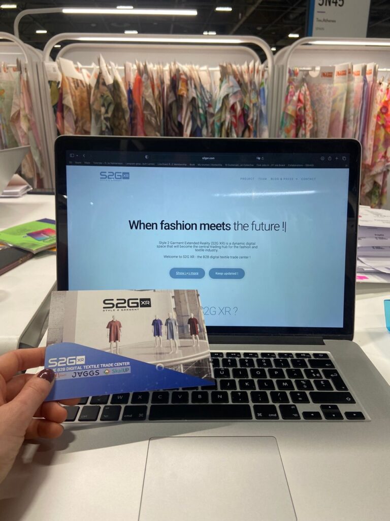 Presentation of the S2G XR platform at Première Vision Paris 2025, with a laptop displaying the website and a project flyer in front of textile samples